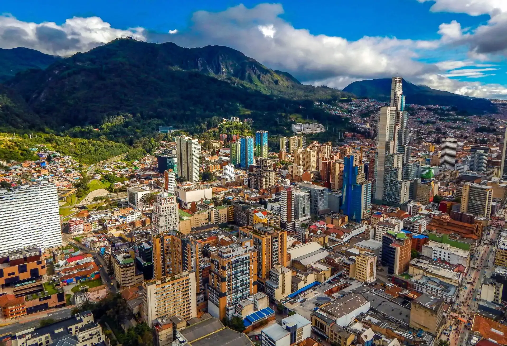 Vista aérea de Bogotá con edificios coloridos y montañas al fondo, destacando vuelos con Avianca en octubre.