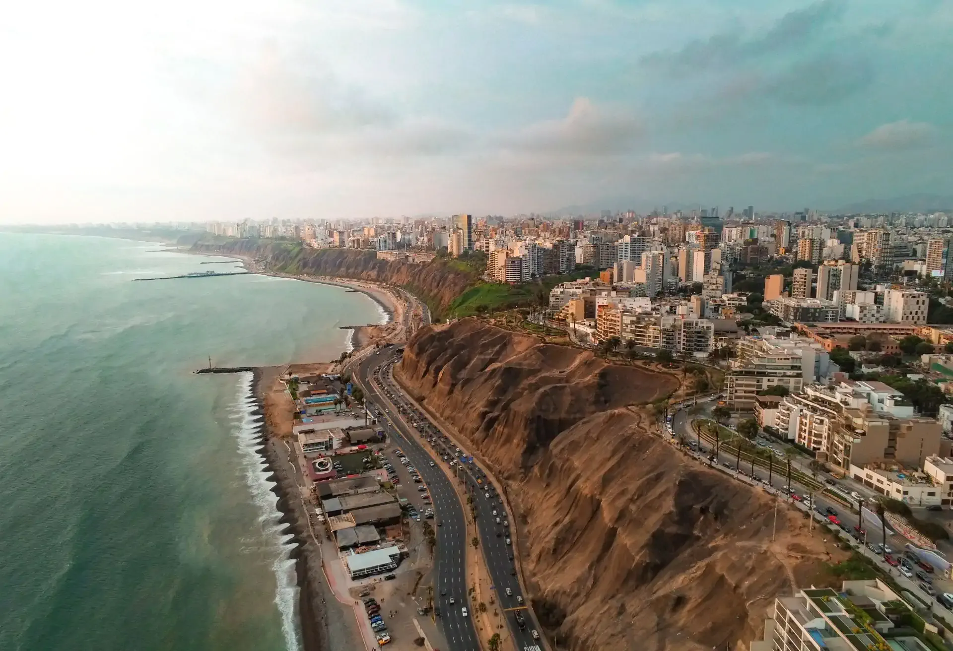Vista aérea de la costa de Lima con acantilados y la ciudad al fondo, en promoción de vuelos desde 320 USD.