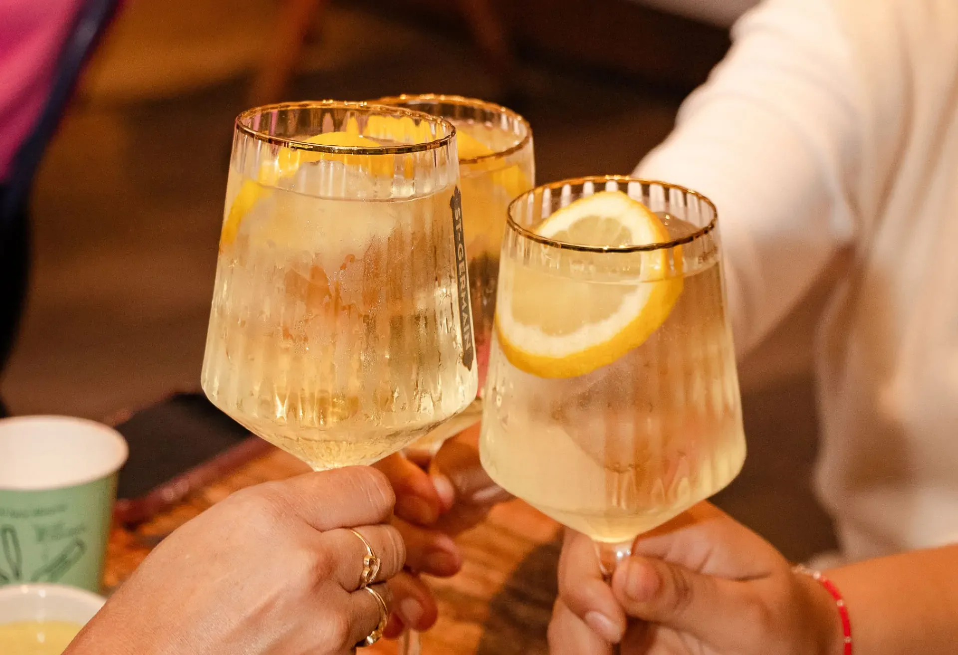 Brindis con copas de St-Germain Spritz, resaltando su frescura floral y el ambiente festivo de la terraza.