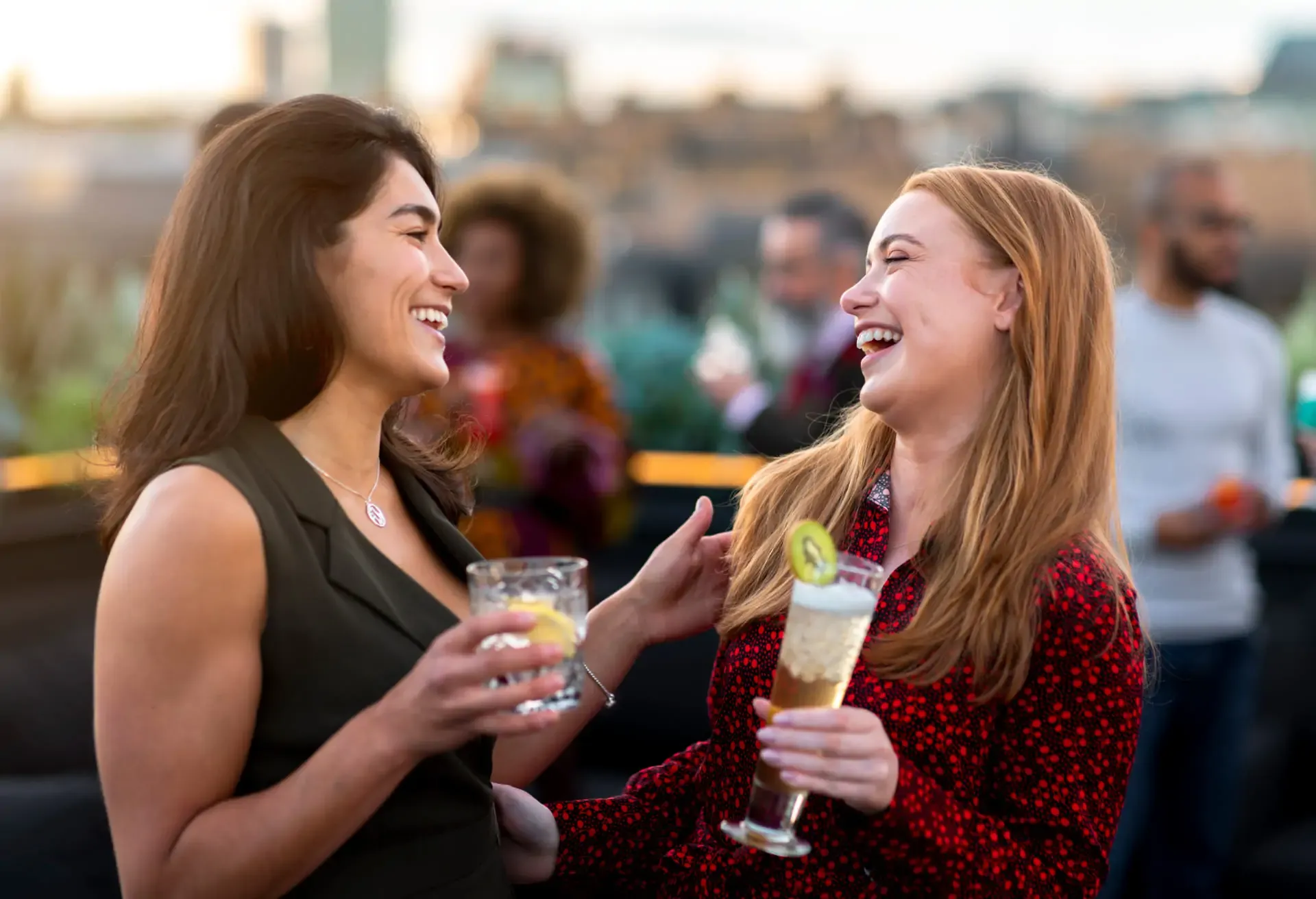 Amigas disfrutando cócteles en terraza al atardecer, compartiendo risas y buena energía con el estilo fresco de St-Germain Spritz.