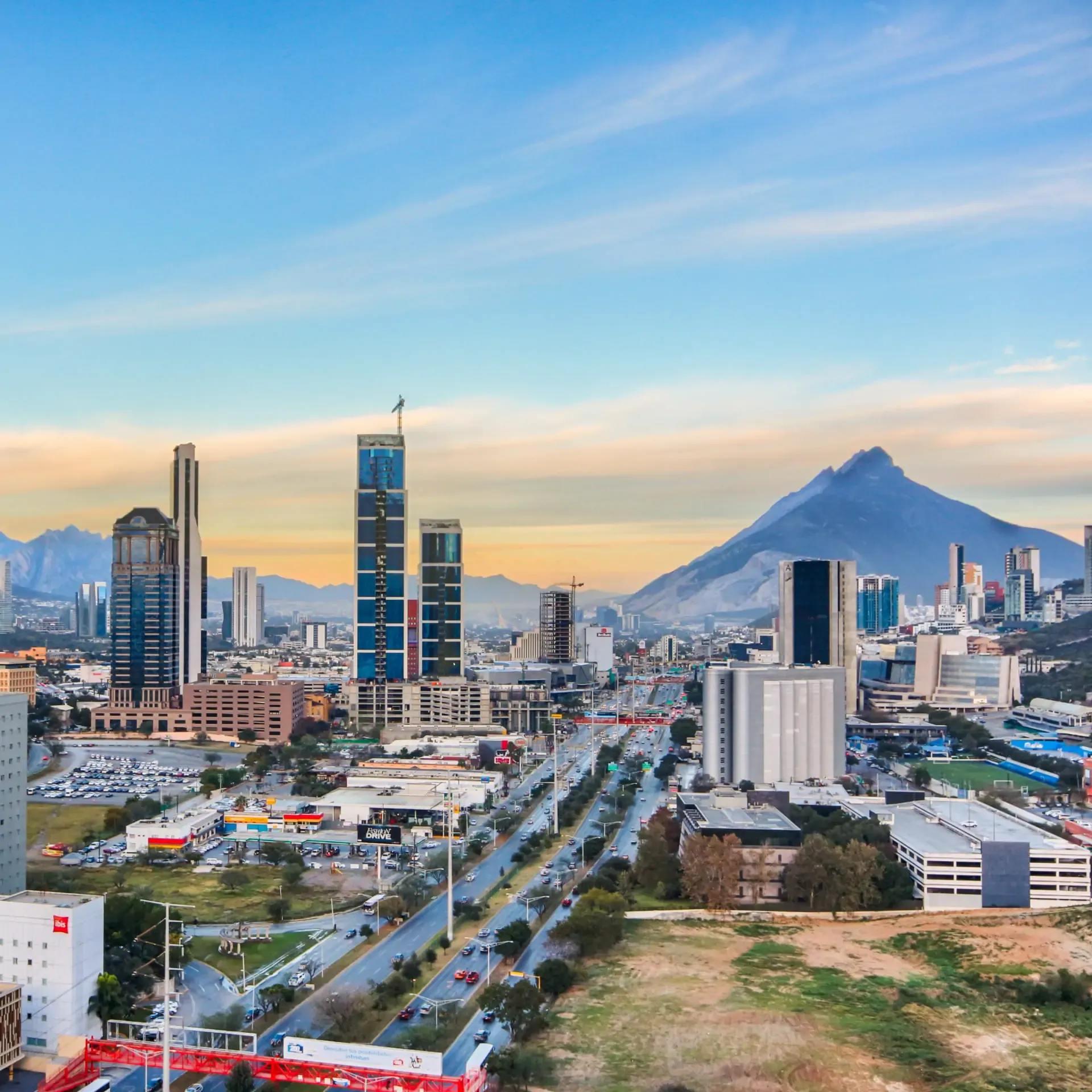 Vista panorámica de la ciudad de Monterrey con el Cerro de la Silla al fondo durante el atardecer.